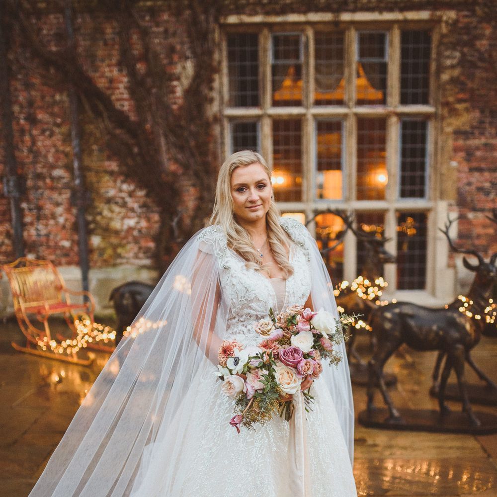 Bride with a side swept hair style in an Enzoani wedding dress with silver thread and lace detail 