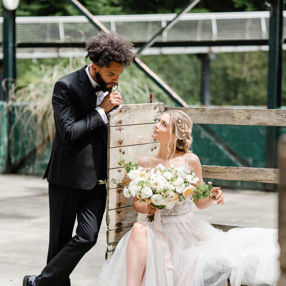 Black groom with afro hair looking at his bride in a tulle wedding dress holding a romantic wedding bouquet 