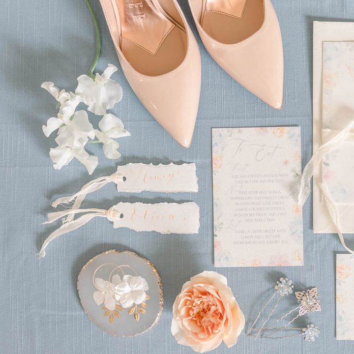 Pastel peach and blue wedding stationery suite flat lay with hair pins, earrings and wedding shoes 