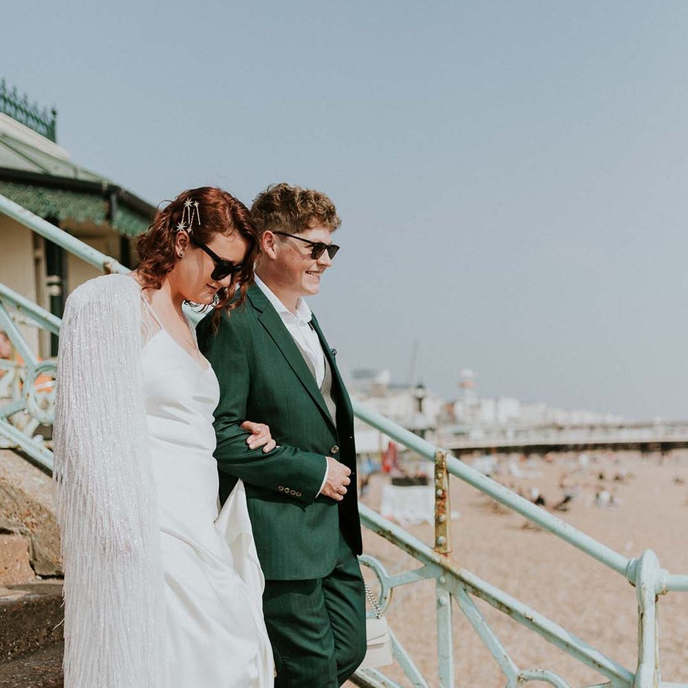 Bride wraps her arms around groom on wedding day by Brighton Pier front