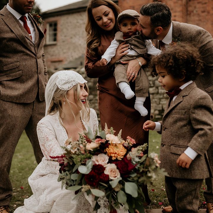 Bride in a lace wedding dress and Juliet Cap veil with her page boys in miniature tweed suits 