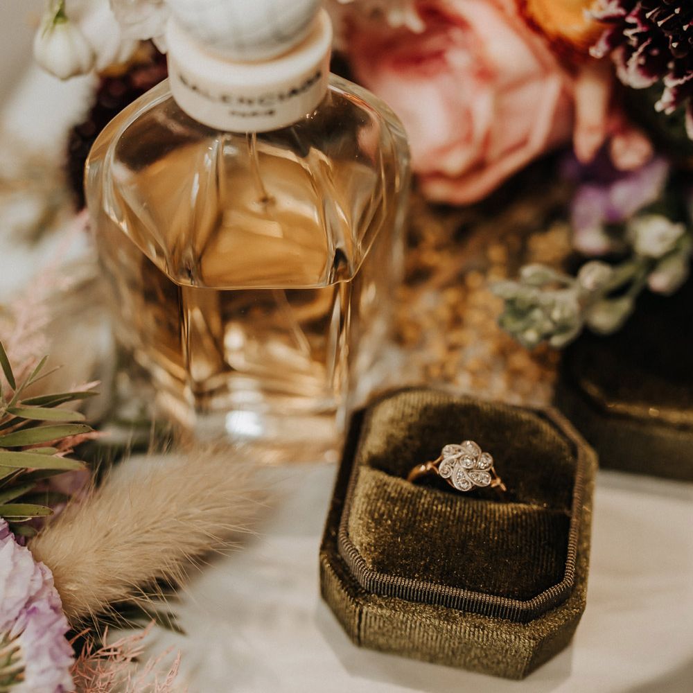 Flower diamond wedding ring in green velvet box next to perfume bottle before wedding