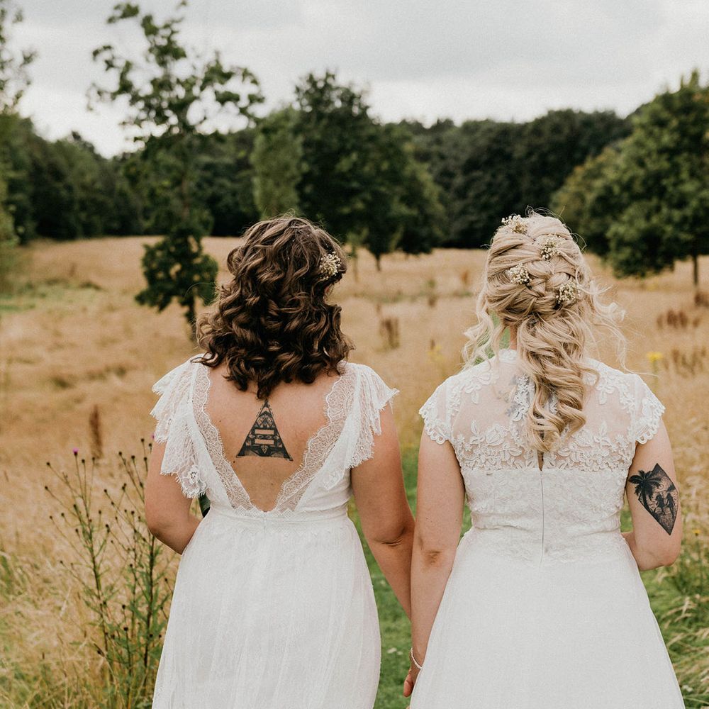 Bride with brunette short curled hair and blond bride with braid hairstyle and gypsophila hair pins walk together