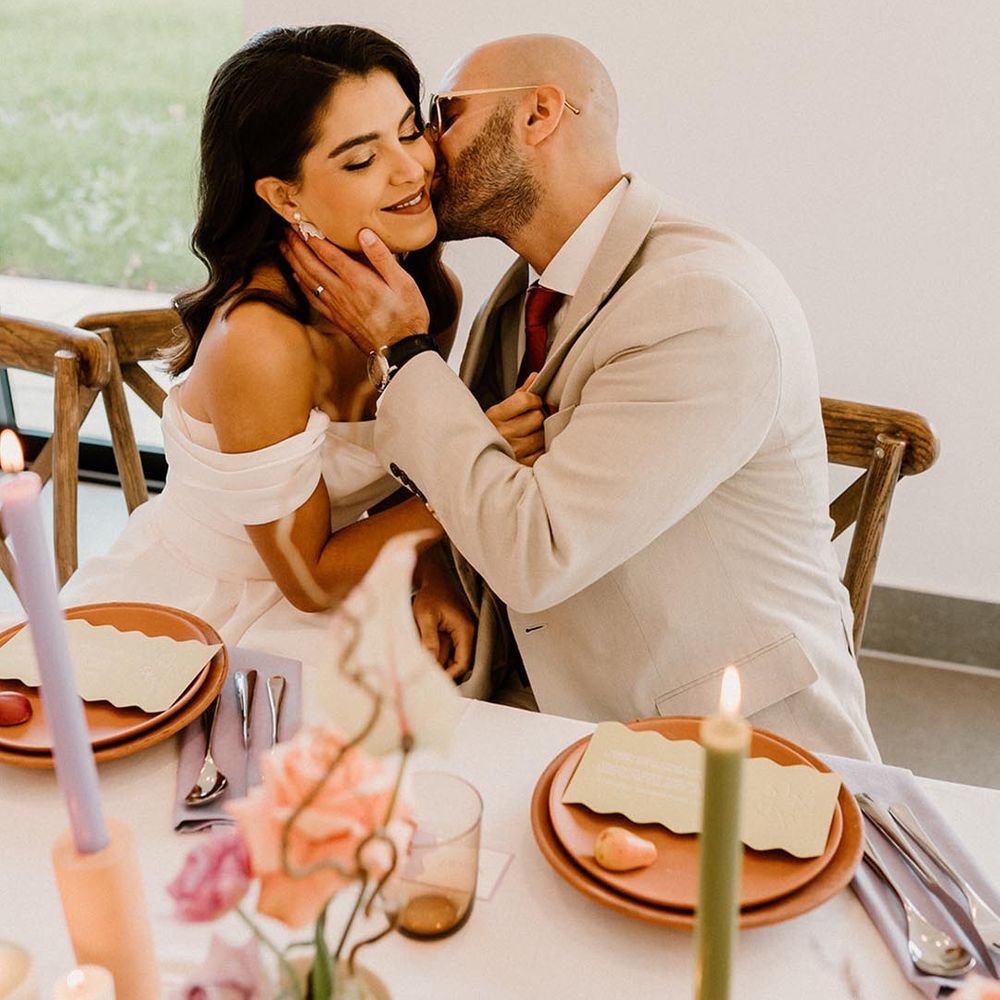 Groom gives the bride a kiss on the cheek on their wedding day 