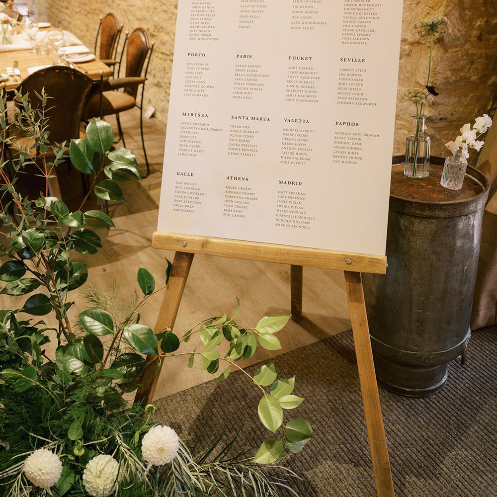 Black and white minimal wedding sign table plan and seating chart with lots of greenery and foliage for rustic luxe wedding 