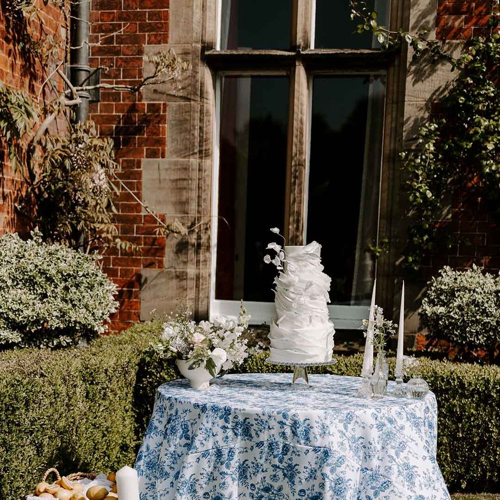 white wedding cake with intricate design on a blue Chinoiserie inspired tablecloth 