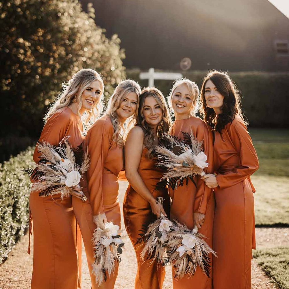 Bridesmaids in mismatched burnt orange bridesmaid dresses with pampas grass bouquets 