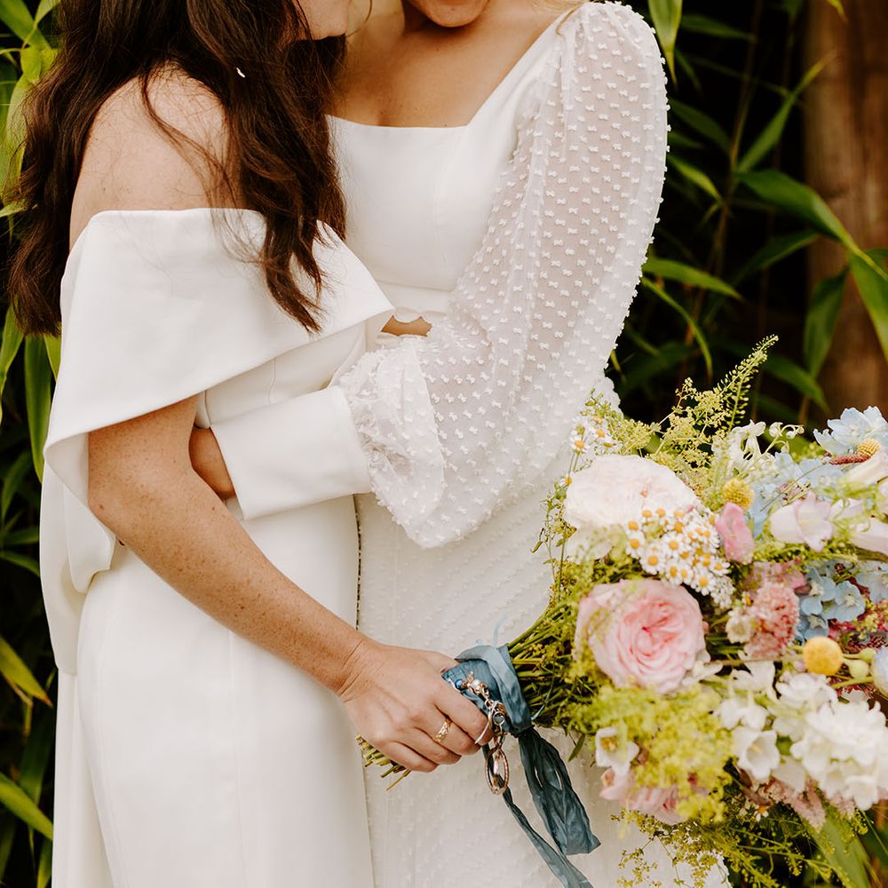 Lesbian wedding with two brides posing for romantic whimsical wedding with wildflower theme 