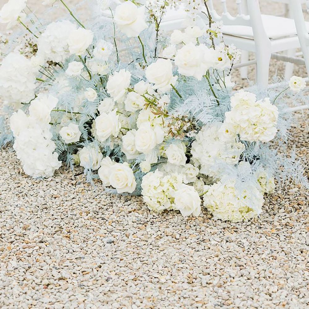 Pastel blue and white wedding aisle flowers with roses and dyed dried grass 