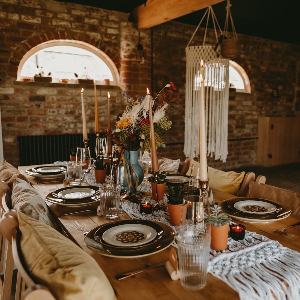 rustic table with macrame table runner, flower centrepieces and candles 