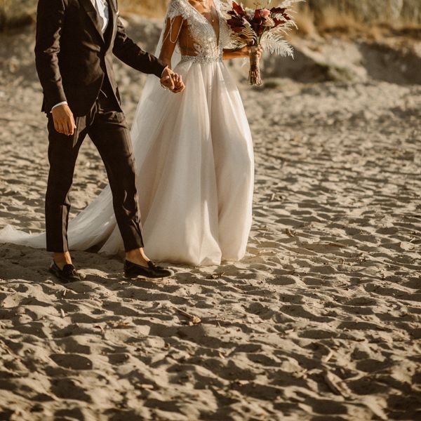 Couple walk together to their beach wedding ceremony