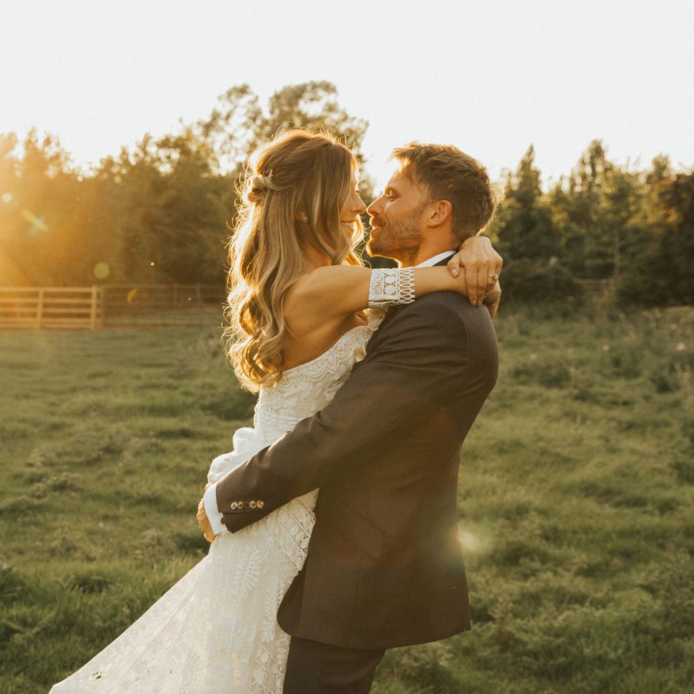 Boho bride and groom hug outside at golden hour