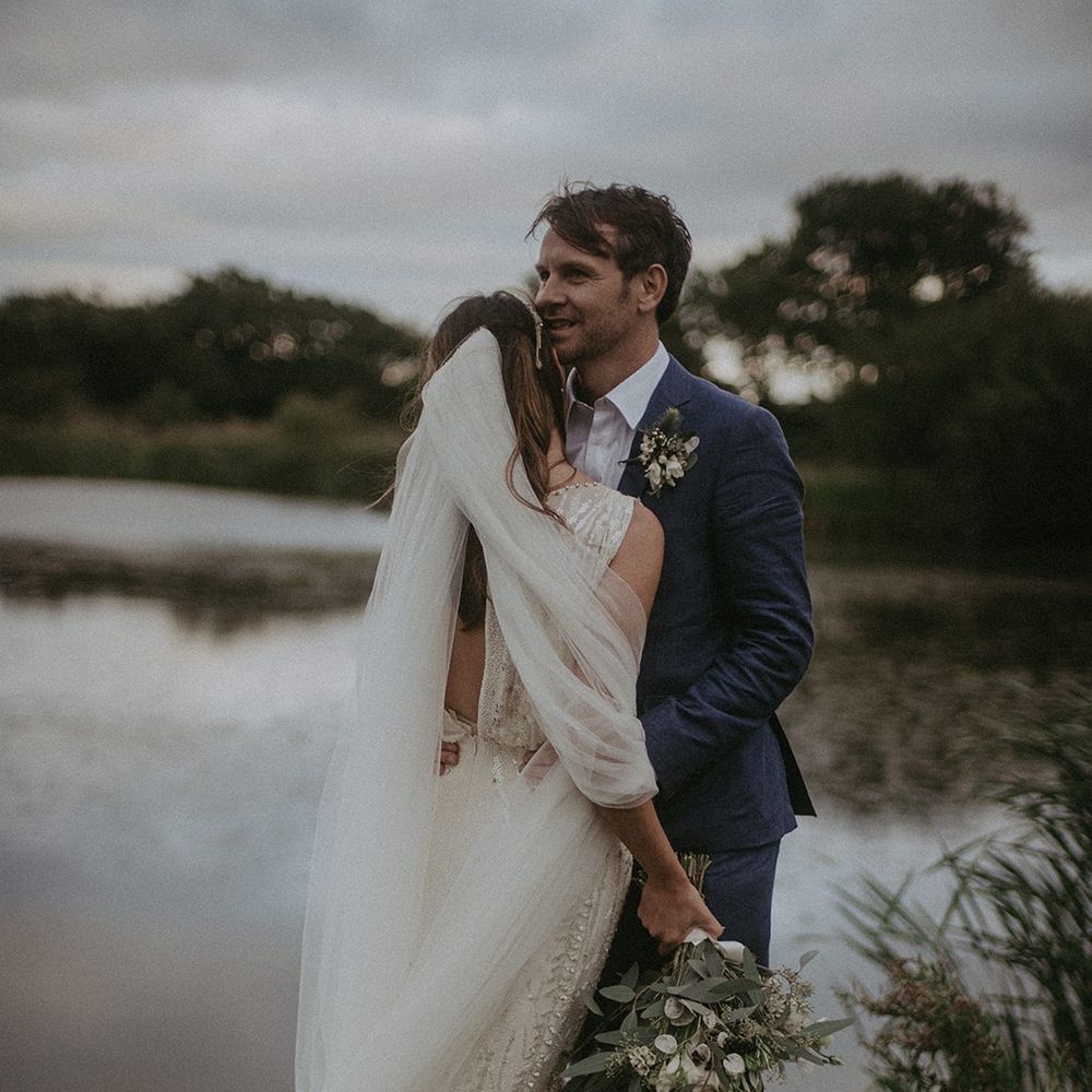 Bride & groom kiss in front of lake 