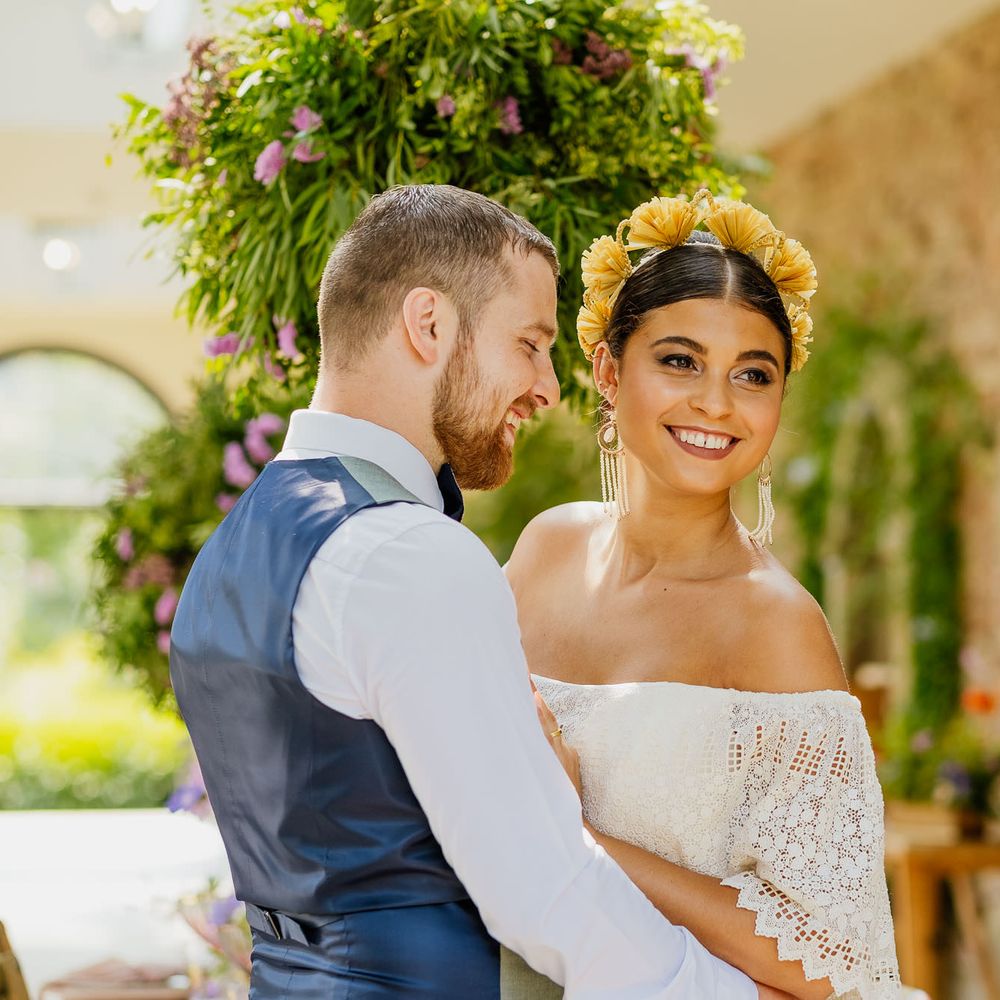 Bride in an off the shoulder layered wedding dress with middle parted bridal updo and yellow headdress 