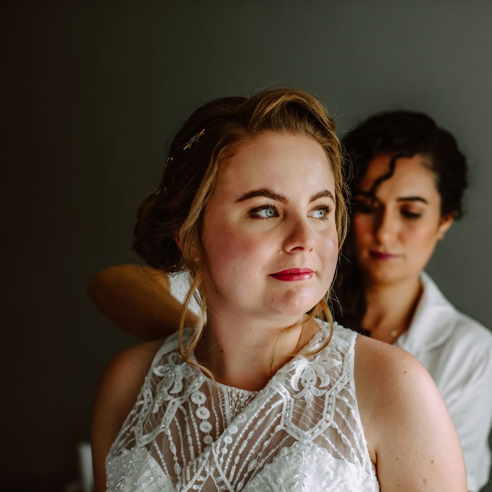 Bride has her dress done up on the morning of her wedding day