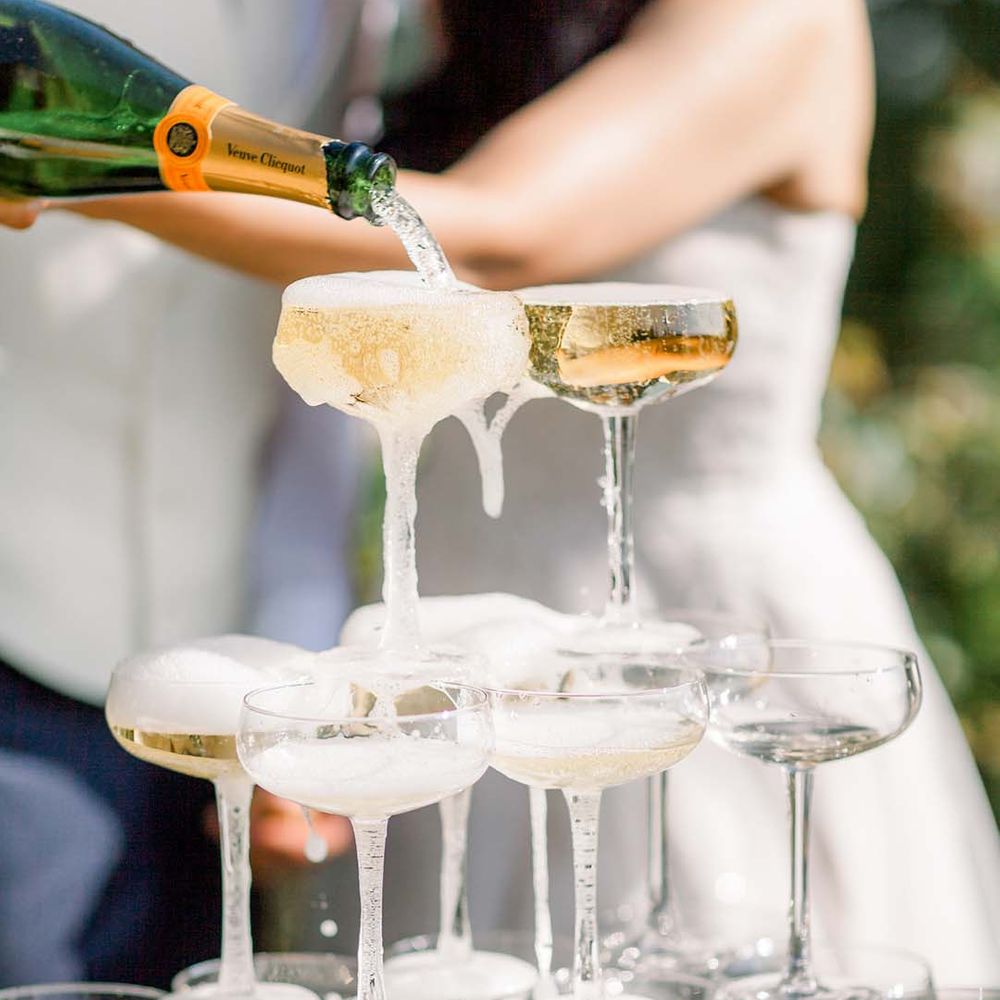 Bride & groom pour champagne into glasses for champagne tower 