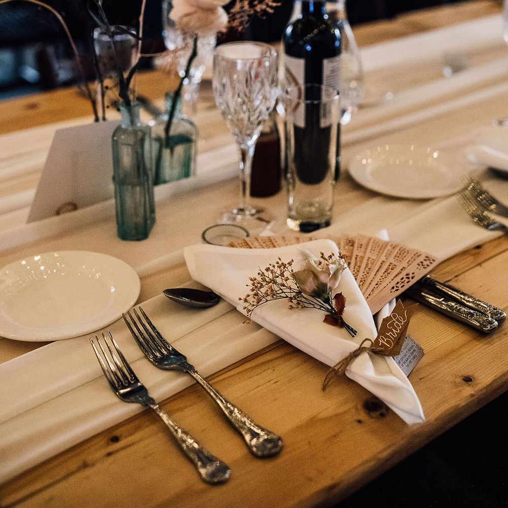 Place setting with wooden fan favours and dried flower decor 