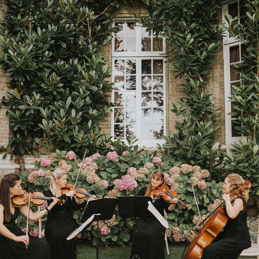 Live wedding music seated outside the wedding venue while guests socialise 