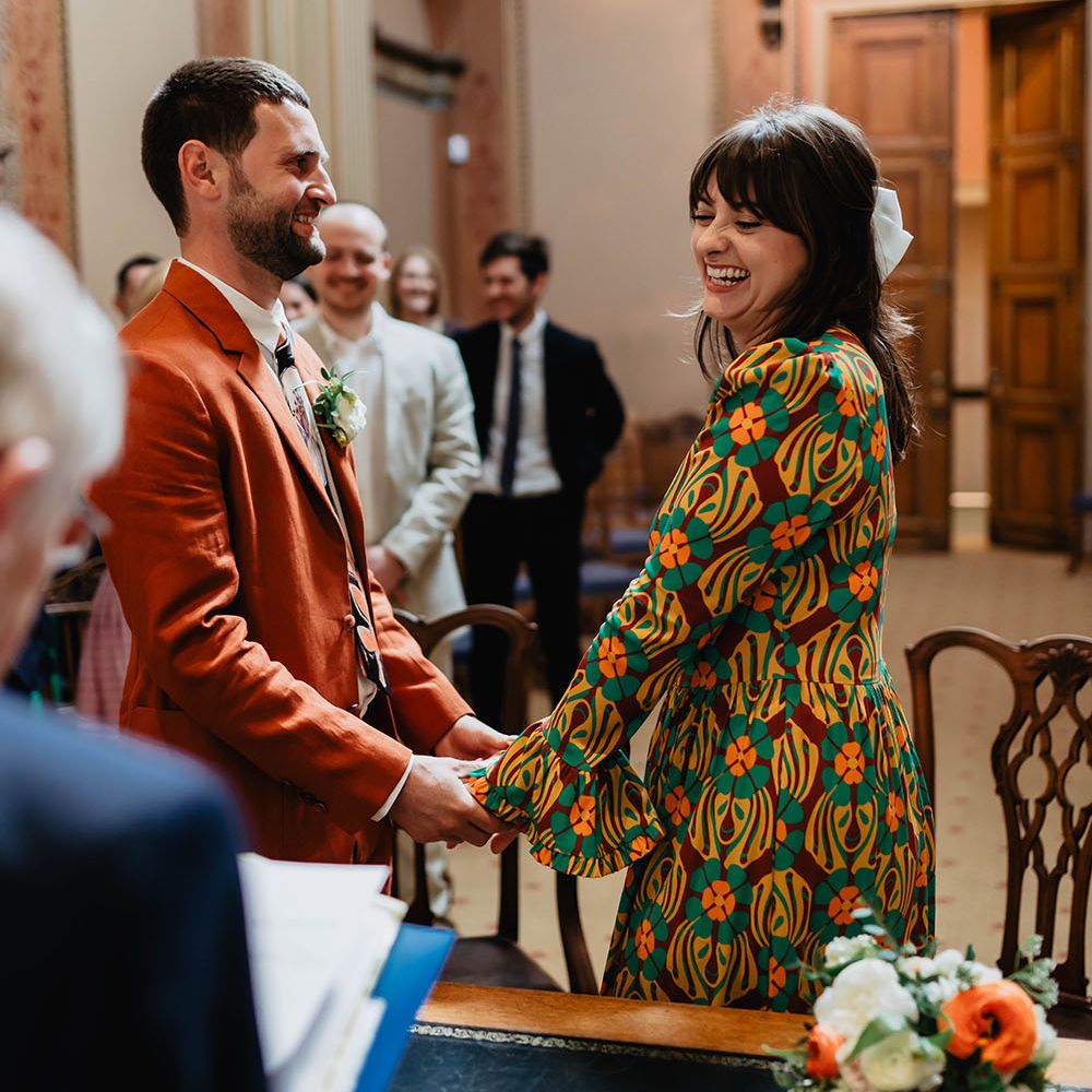Bride & groom hold hands during wedding ceremony in Bristol for colourful and relaxed day 