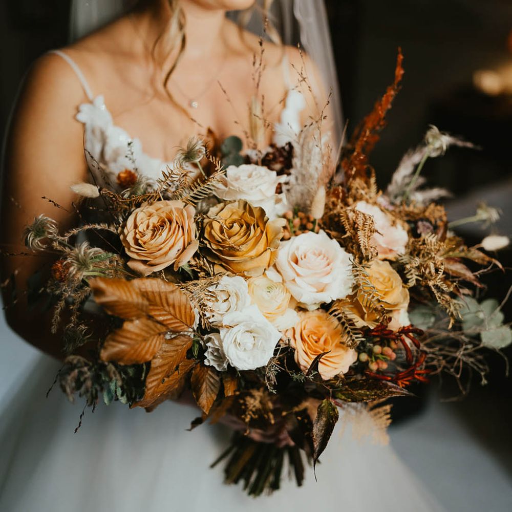 Autumnal wedding bouquet with white and toffee roses, autumn leaves and dried grasses 