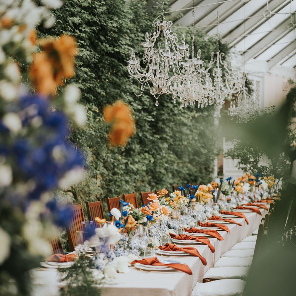 Blue and orange wedding flowers and tablescape with chandeliers 
