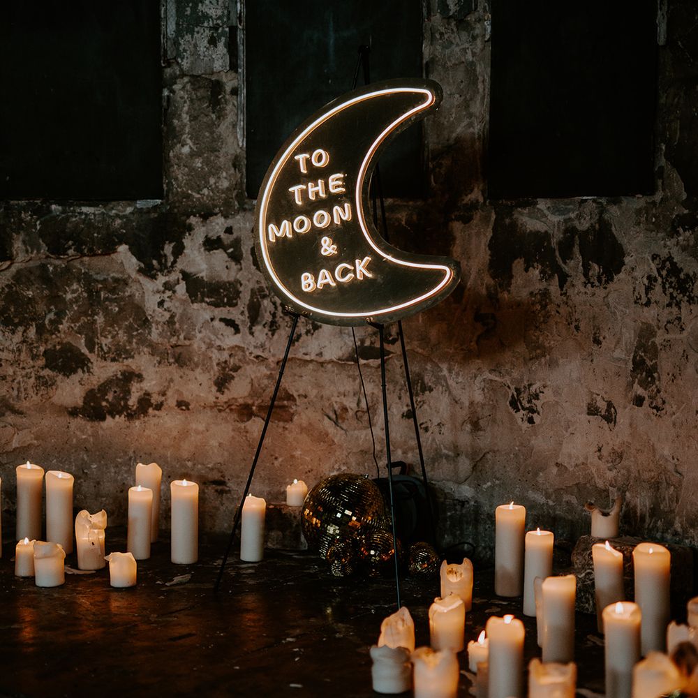 Celestial wedding lighting created by a moon neon sign and candles