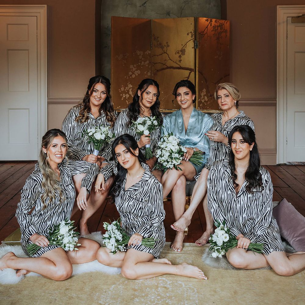 Bridesmaids and mother of the bride in black and white striped pyjamas with the bride in a blue satin robe as they get ready for the wedding 