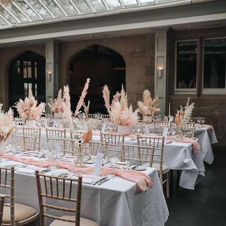 Pink and white pampas grass centrepiece decor lining the tables for the reception at Hampton Manor venue 