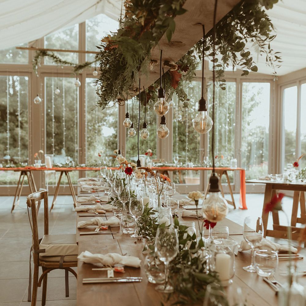 Hanging floral installation with festoon lighting over the wedding table at Trevenna Barns wedding venue in Cornwall 