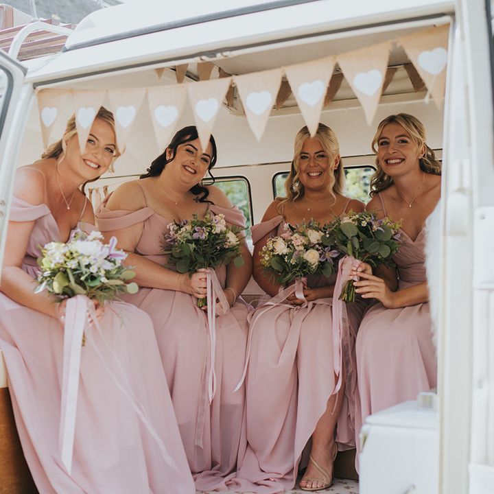 Bridesmaids in pink off the shoulder bridesmaid dresses holding their bouquets sitting in cream VW transportation 