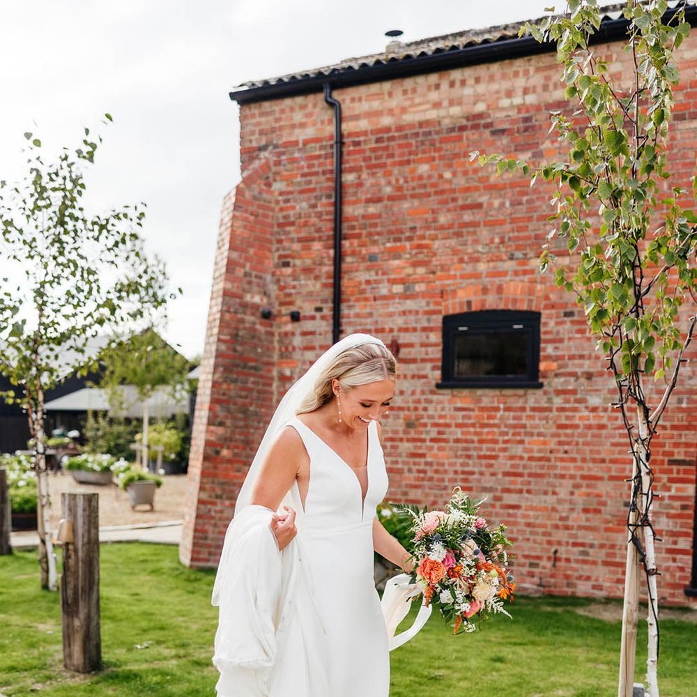 Bride in Savin London wedding dress with white bow wedding shoes and dainty pearl earrings 