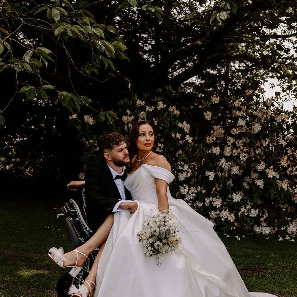 inter able couple wedding photographs with bride in a princess wedding dress sitting on her grooms lap 