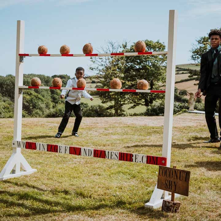 Wedding guests playing Coconut Shy outdoor wedding game on grounds of Tredudwell Manor