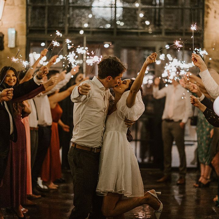 The bride and groom wave sparklers with their guests at the end of the wedding day 