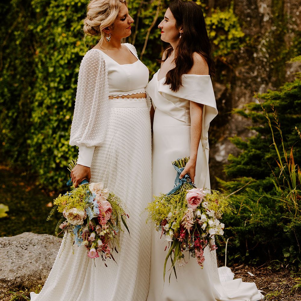 Bride in textured spotted long sleeve top and skirt separates with bride in off the shoulder gown and pearl hair piece at same sex lesbian wedding 