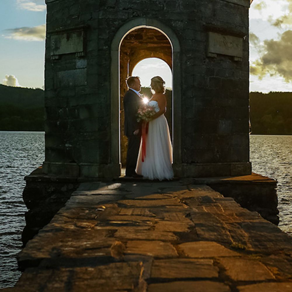 The bride and groom pose for their wedding photos with a view of the sea 