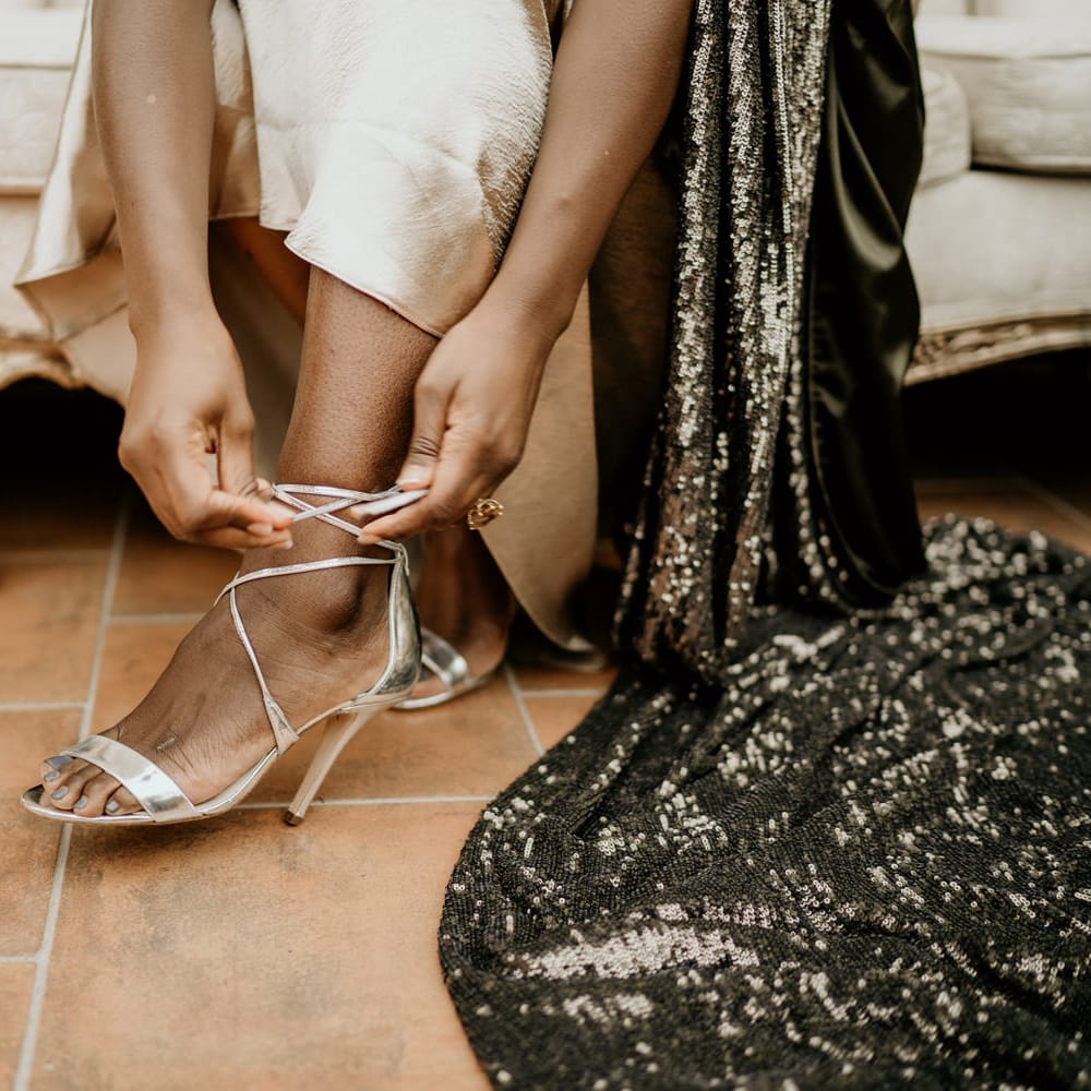 Bride with silver toe polish putting on her silver sandal wedding shoes 