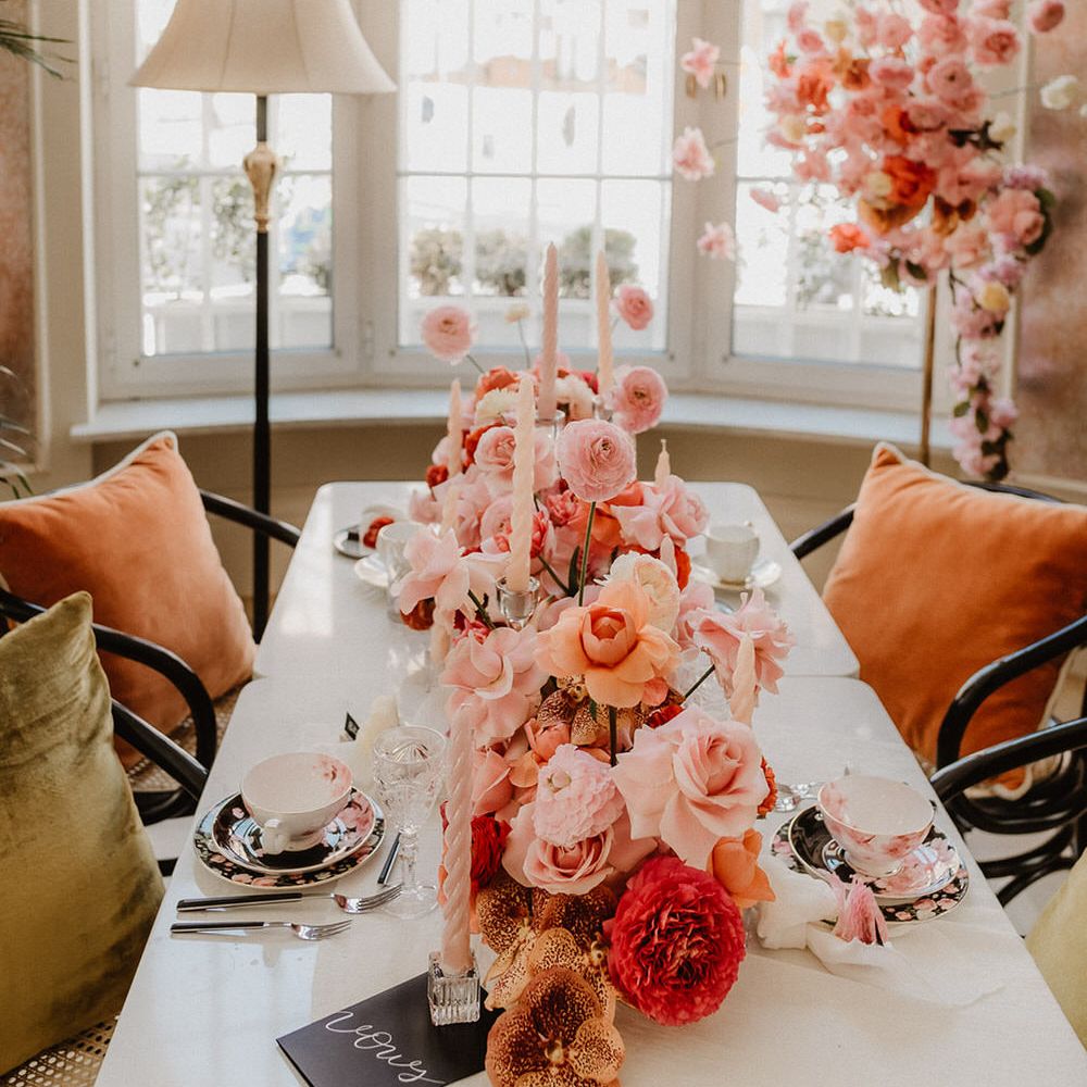 Luxe wedding tablescape with peach wedding flowers including pink, peach and burgundy ranunculi, garden roses and orchids