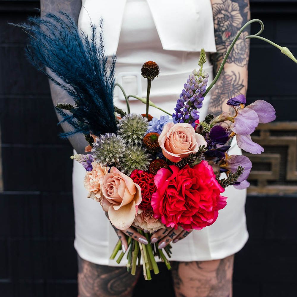 Bright red, purple and teal jewel wedding bouquet with roses, pampas grass and stocks 