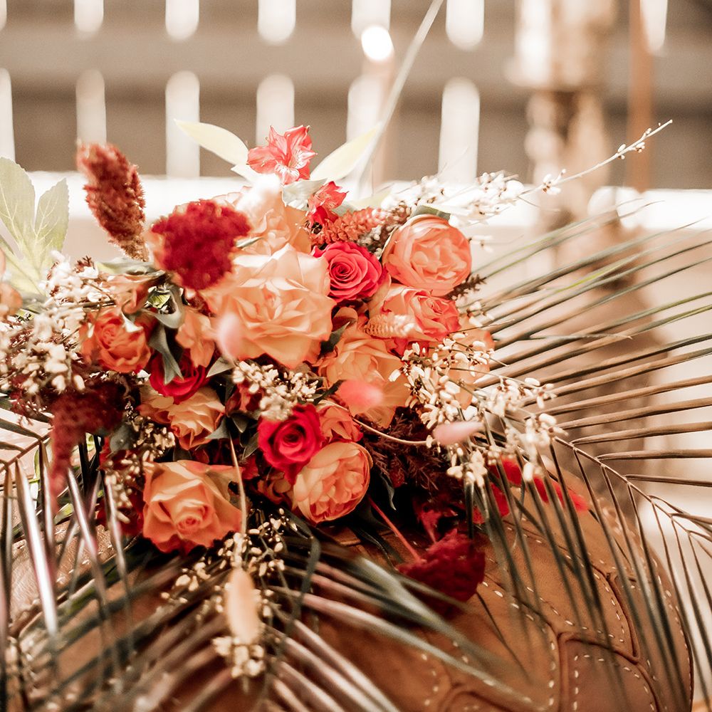 Orange and red rose and dried grass floral arrangement 