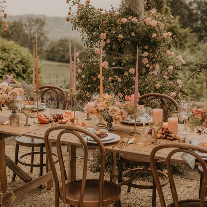 Outdoor summer wedding table decor with taper candles, centrepiece flowers and elegant tableware 