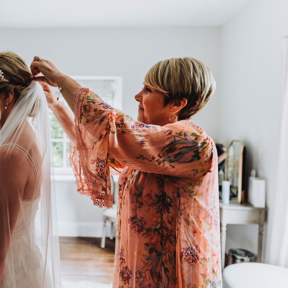 Wedding guest applies veil to brides hair on her wedding day