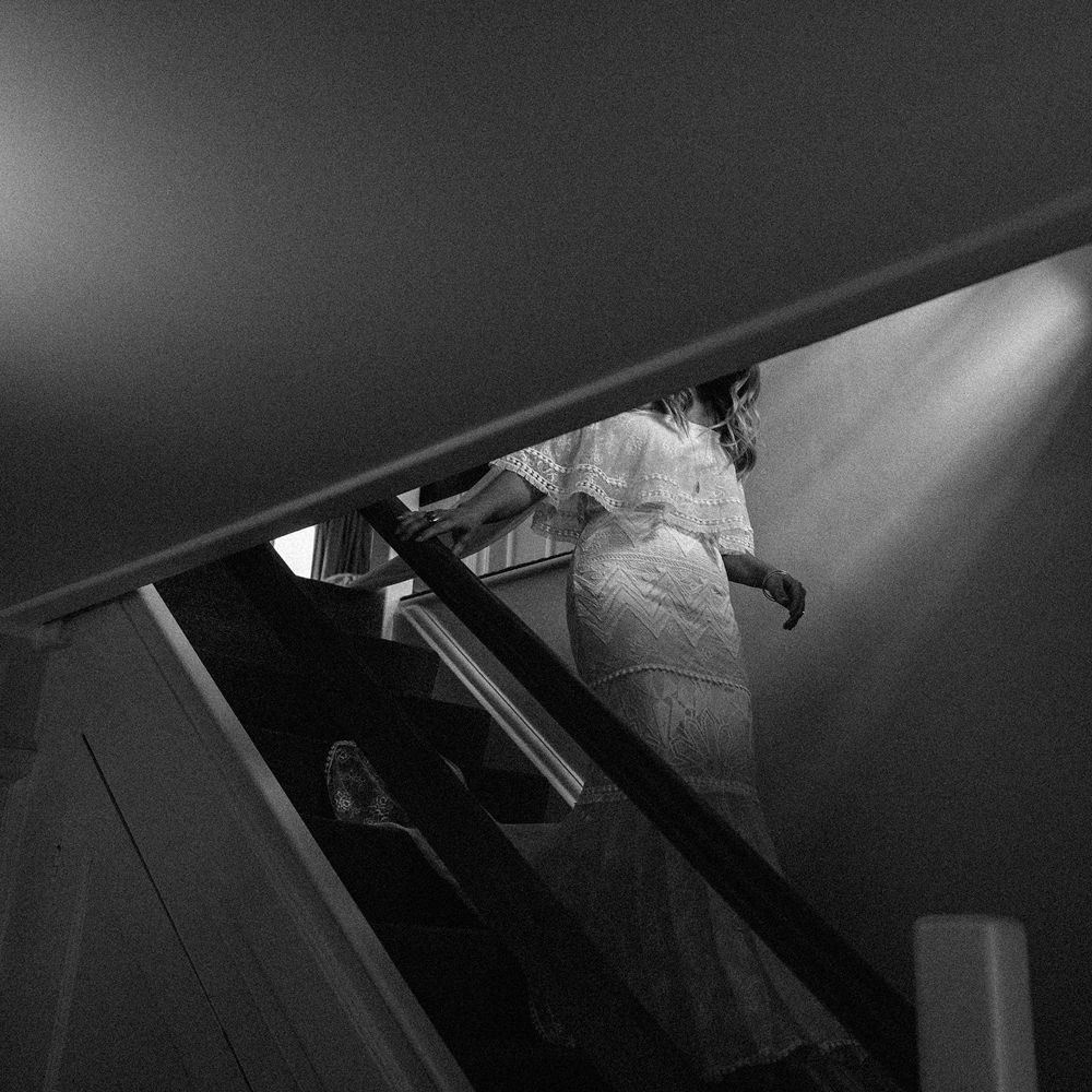 Bride in Grace Loves Lace Bardot wedding dress walking down the stairs before Isle of Wight wedding with macrame wedding decor