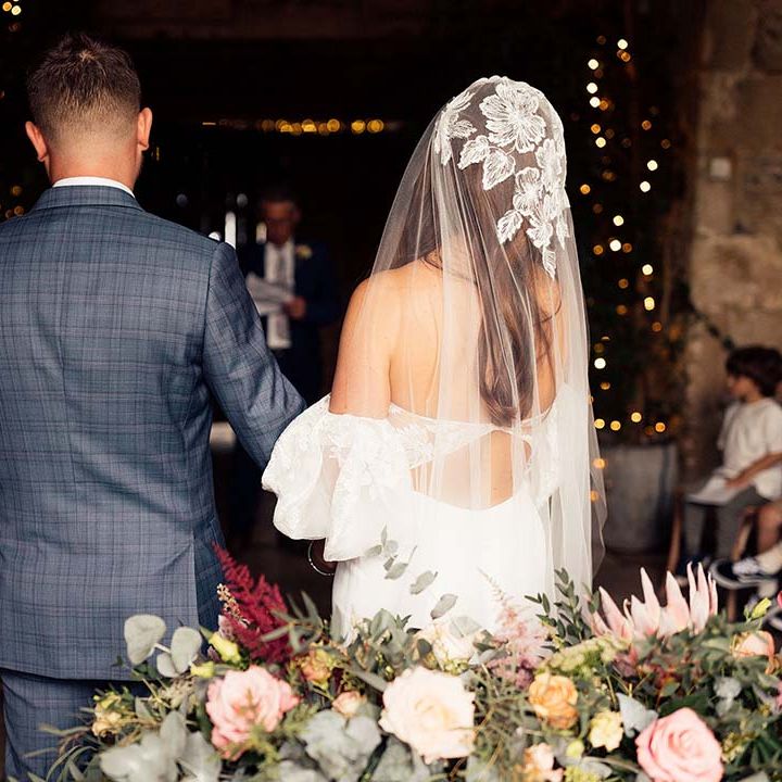 Bride in a strapless wedding dress with lace and puff sleeve detail matching her wedding veil standing next to her husband 