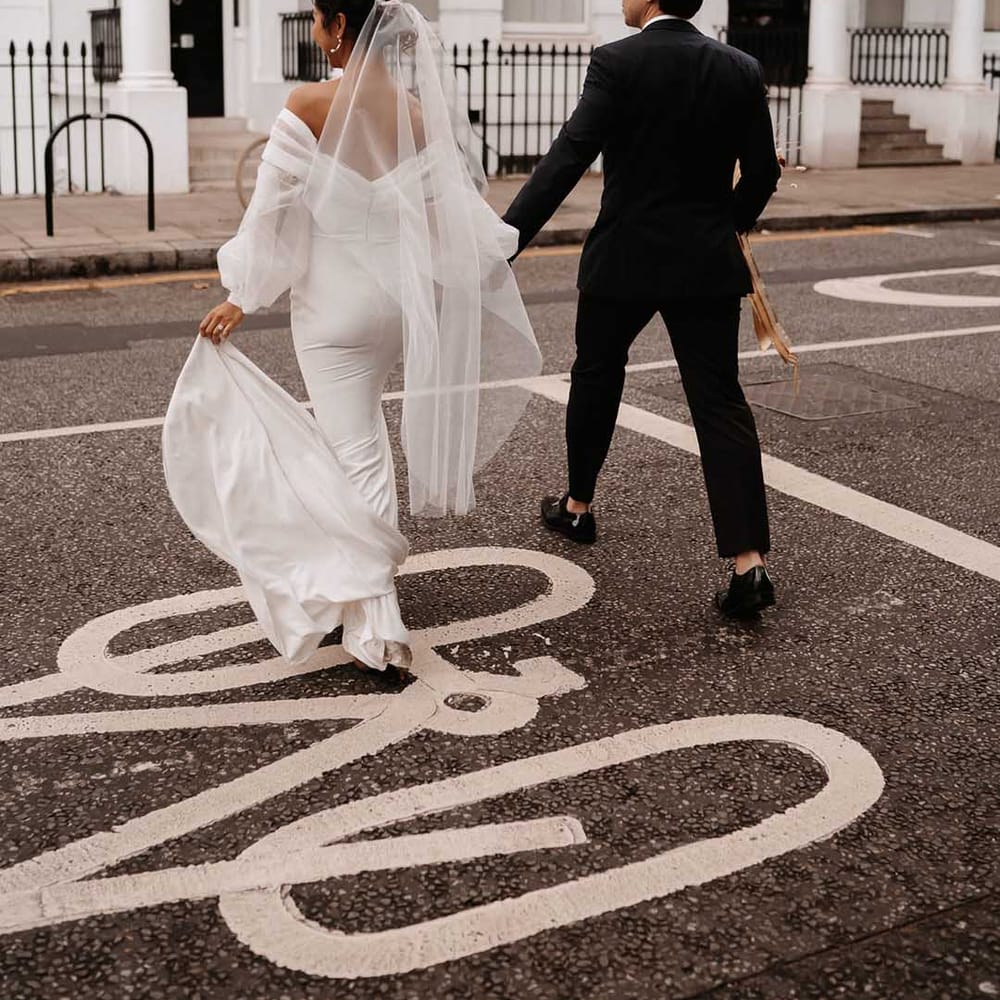Bride wearing fitted silk wedding dress holding grooms hand in Chelsea 