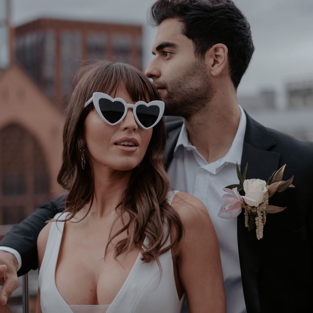 Bride in white love heart sunglasses and plunging V neck wedding dress at Manchester Hall city wedding 