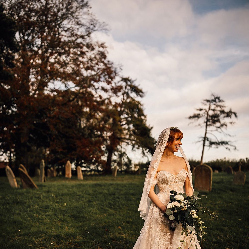 Bride clutches large bouquet in lace detail wedding dress and lace trim veil