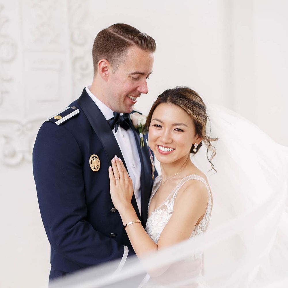 Bride leans in to her groom as her veil blows around her