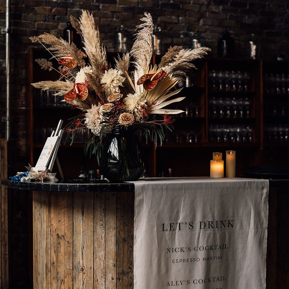 Fabric bar menu sign and dried pampas grass, anthurium and dahlia wedding flower arrangement 