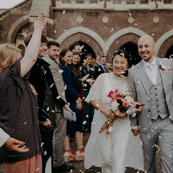 Bride & groom walk through confetti as bride wears wedding dress sample complete with cape  | Irene Yap Photography